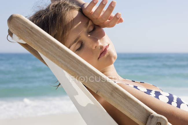 Primo piano della donna che riposa sulla sedia a sdraio sulla spiaggia — Foto stock