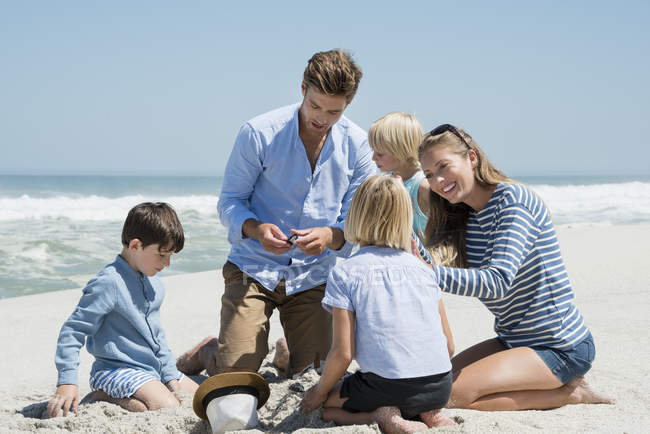 Família feliz brincando na areia na praia — Fotografia de Stock