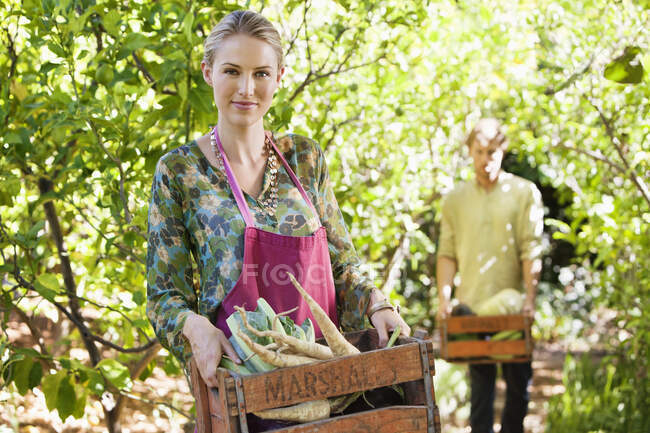 Smiling woman holding a crate of radish — Stock Photo