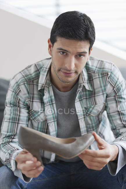Man sitting on couch and holding high heel shoe — Stock Photo