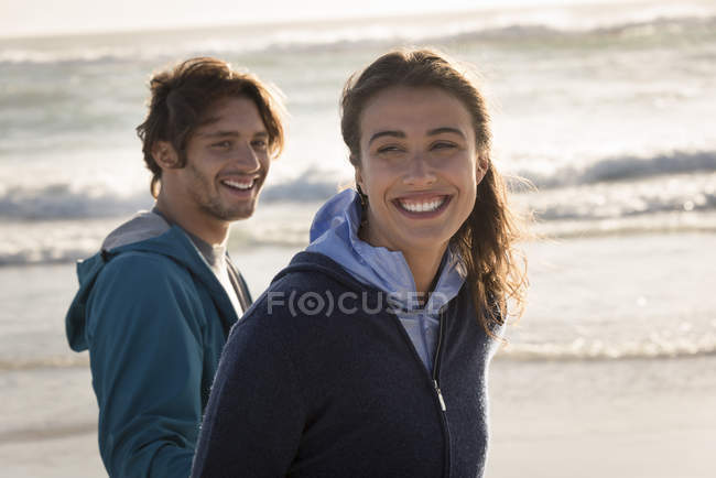 Riendo pareja joven caminando en la playa en otoño - foto de stock