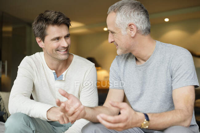 Dos amigos masculinos discutiendo y sonriendo - foto de stock