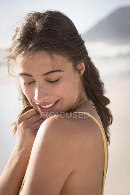 Encantadora jovem mulher olhando sobre ombro na praia — Fotografia de Stock