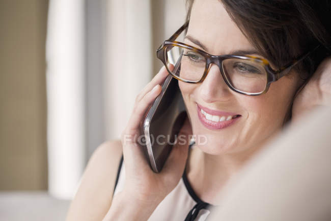 Крупный план улыбающейся женщины, разговаривающей по мобильному телефону — стоковое фото