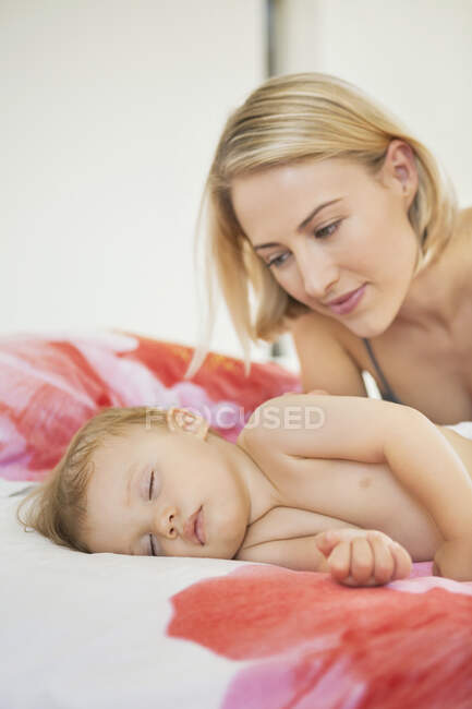Frau sieht ihr Baby schlafend auf dem Bett an — Stockfoto
