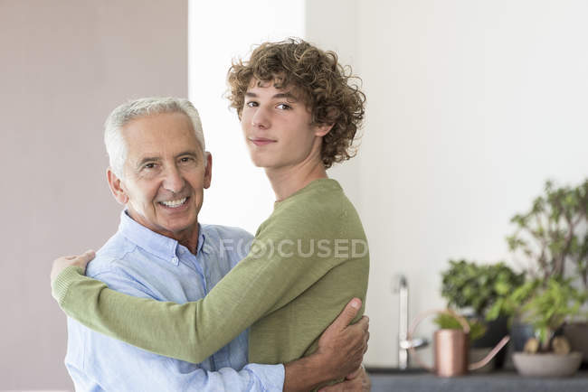 Портрет счастливого пожилого мужчины, обнимающего внука — стоковое фото