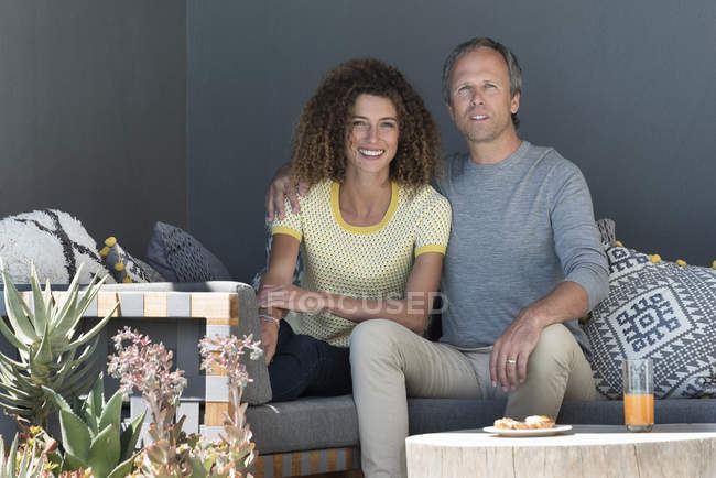 Porträt eines glücklichen Paares, das mit Essen auf der Couch sitzt — Stockfoto