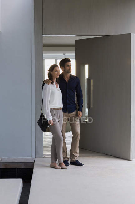 Couple debout à la porte de la maison et regardant autour — Photo de stock