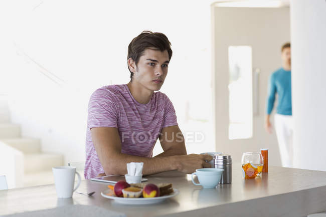 Joven reflexivo desayunando en casa - foto de stock