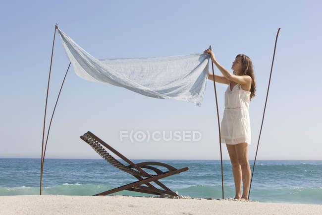 Woman fixing canopy on sandy sea beach — Stock Photo