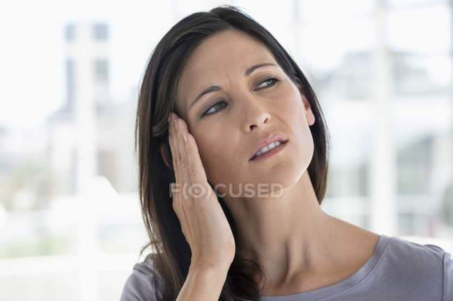 Close-up de mulher que sofre de dor de cabeça em fundo embaçado — Fotografia de Stock