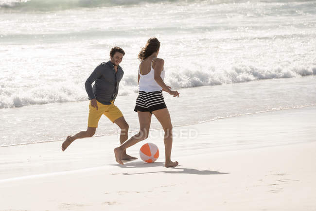 Feliz jovem casal jogar bola de praia — Fotografia de Stock