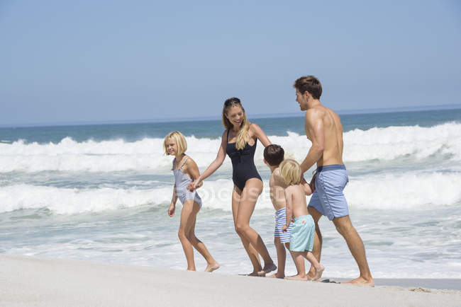 Heureuse famille marchant sur la plage se tenant la main — Photo de stock