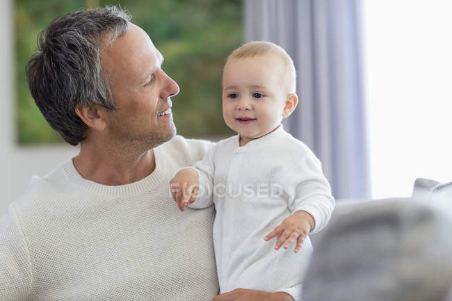Feliz padre sosteniendo lindo bebé hija en casa - foto de stock