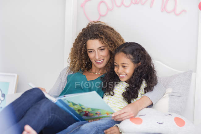Mãe e filha lendo livro na cama em casa — Fotografia de Stock
