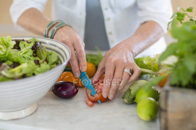 Close-up de mãos femininas cortando legumes na cozinha — Fotografia de Stock