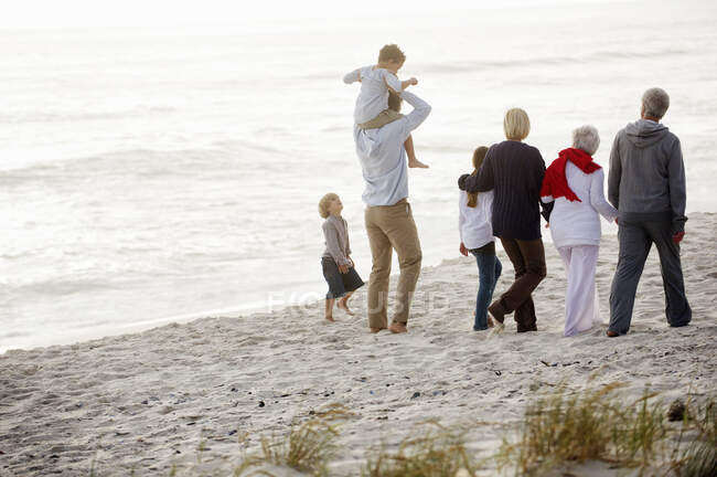 Família de várias gerações caminhando na praia — Fotografia de Stock
