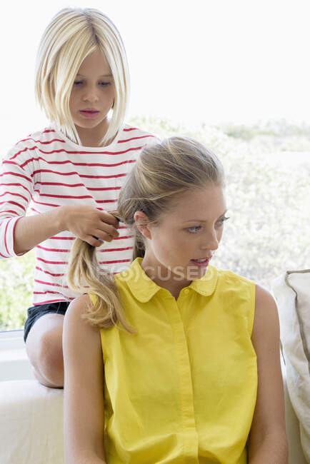 Mädchen macht Pferdeschwanz mit den Haaren ihrer Mutter im Wohnzimmer — Stockfoto