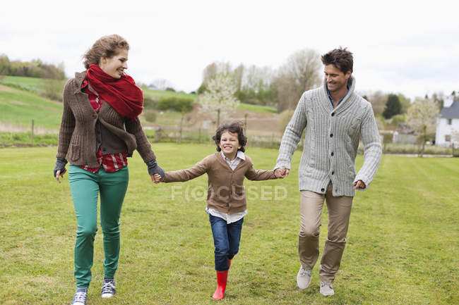 Felice famiglia a piedi nel campo verde — Foto stock
