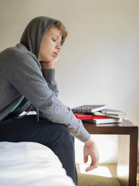 Teenage boy sitting on the bed and thinking — Stock Photo