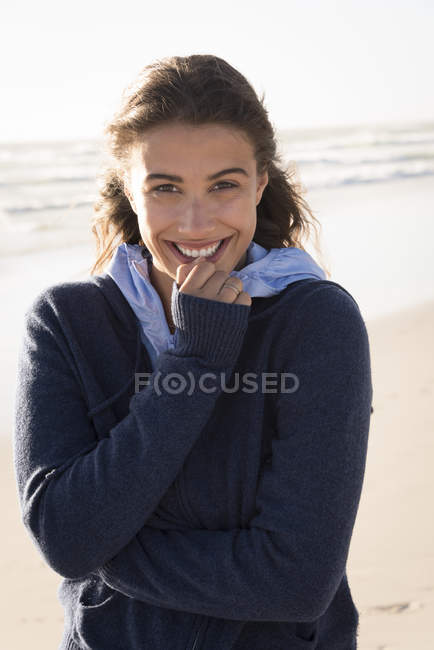 Porträt einer jungen, charmanten Frau in warmem Kapuzenpulli am Strand — Stockfoto