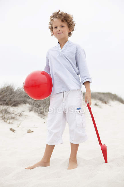 Junge mit Spielzeugschaufel und Ball am Sandstrand — Stockfoto