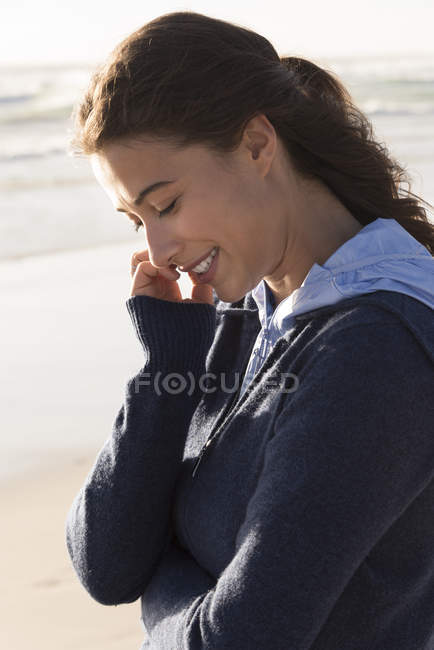 Charmante junge Frau im Kapuzenpulli steht am Strand — Stockfoto