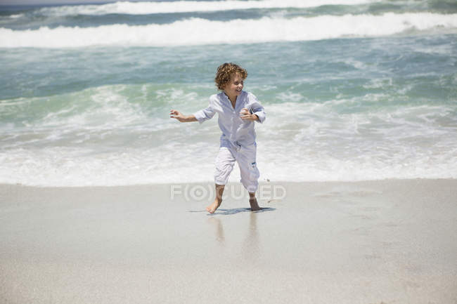Smiling boy playing on sandy beach — Stock Photo