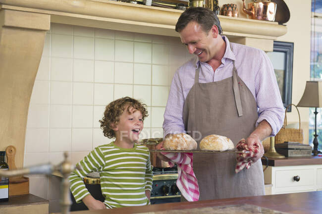 Симпатичный маленький мальчик смотрит на хлеб в руке отца — стоковое фото