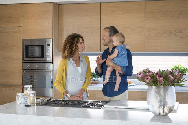 Glückliches Paar steht mit kleiner Tochter in Küche — Stockfoto