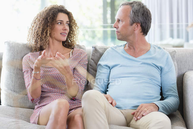 Счастливая пара разговаривает на диване в гостиной — стоковое фото