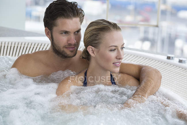 Retrato de pareja de risa relajada descansando en bañera de hidromasaje - foto de stock