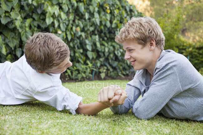 Two boys arm wrestling on grass — Stock Photo