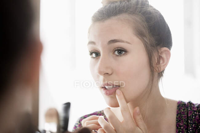 Teenage girl looking her face on mirror — Stock Photo