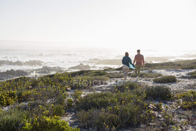 Coppia rilassata a piedi sulla costa con vegetazione — Foto stock