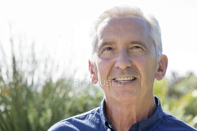 Портрет вдумливого старшого чоловіка, який посміхається в саду — стокове фото