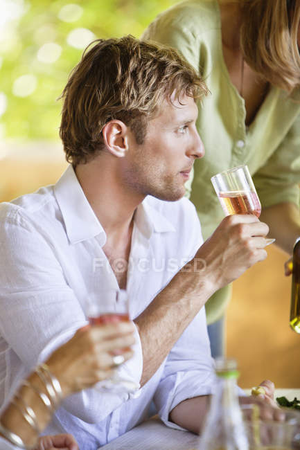 Homem segurando copo de bebida enquanto sentado ao ar livre — Fotografia de Stock