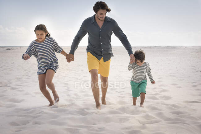 Счастливый отец бегает со своими детьми на пляже — стоковое фото