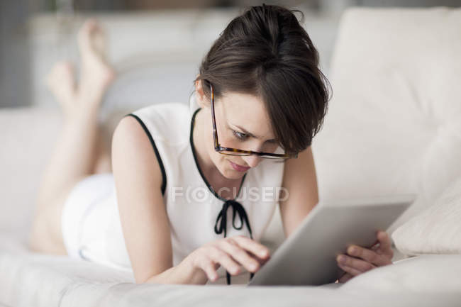 Mulher deitada na cama e usando tablet digital — Fotografia de Stock