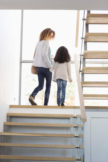 Happy mother and daughter walking on staircase — Stock Photo