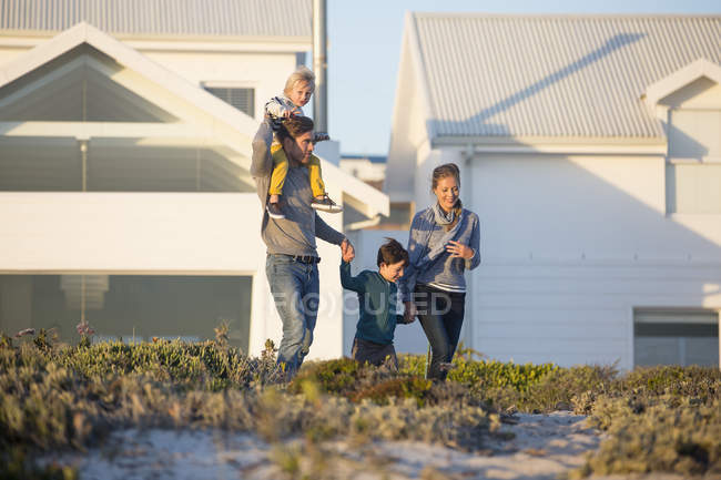 Família feliz andando em frente a casa no campo — Fotografia de Stock