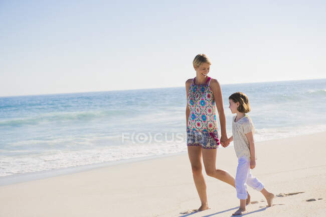 Женщина, гуляющая по пляжу со своей дочерью — стоковое фото