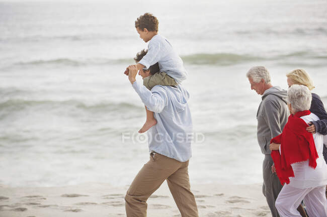 Família de várias gerações caminhando na praia — Fotografia de Stock
