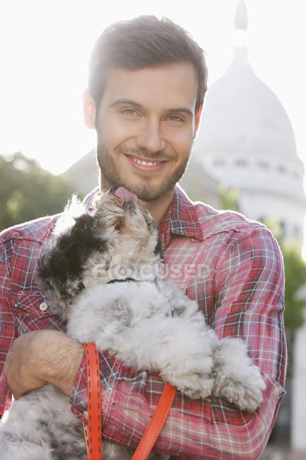 Man carrying puppy in city and looking away — Stock Photo