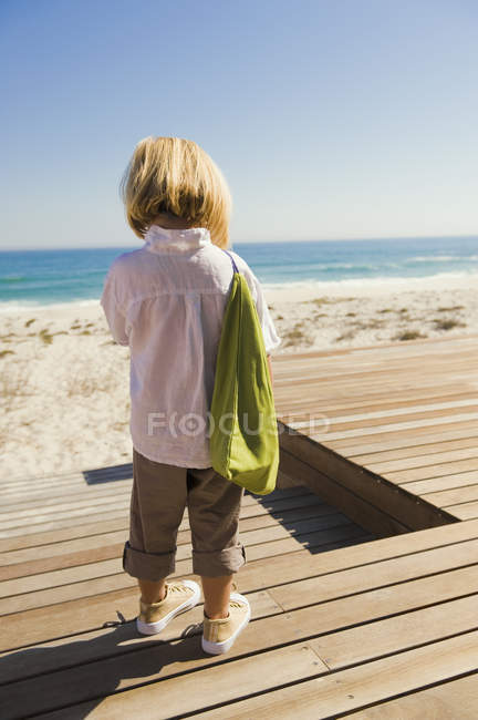 Little girl standing on boardwalk on sea coast — Stock Photo
