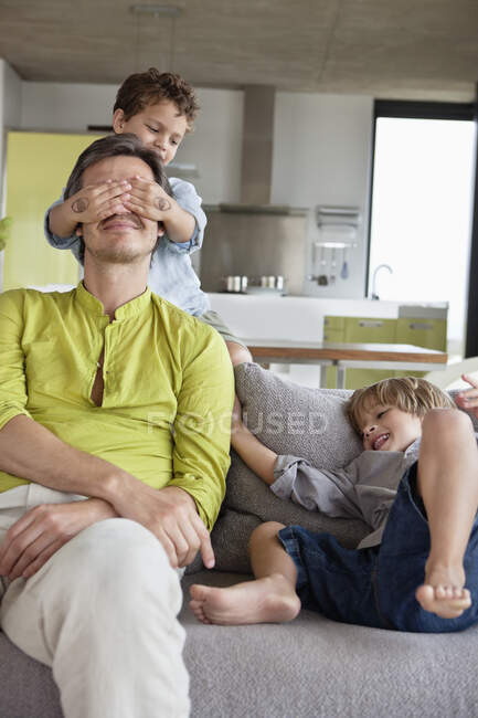 Мальчик закрывает глаза своего отца своим братом — стоковое фото