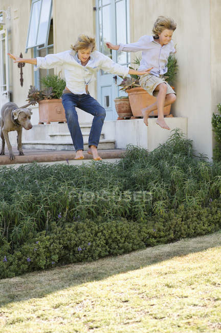 Teenage boys jumping in air against house — Stock Photo
