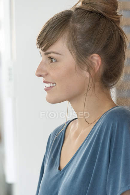 Крупный план улыбающейся молодой женщины, которая смотрит в сторону — стоковое фото