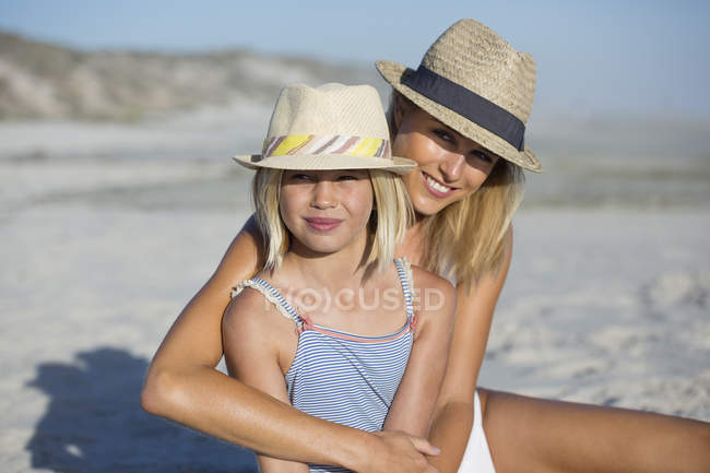 Portrait de femme heureuse et fille assise sur la plage — Photo de stock