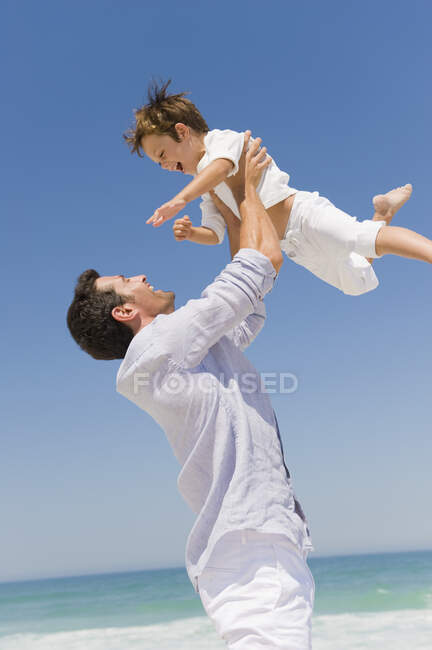 Мужчина играет со своим сыном на пляже — стоковое фото